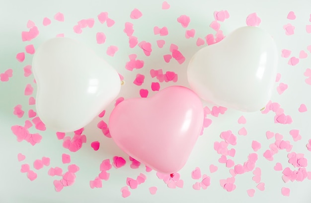 Valentinstag-Komposition Weißer Hintergrund mit weißen und rosafarbenen Luftballons in Herzform und Konfetti