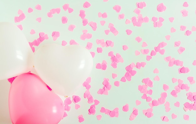 Valentinstag-Komposition Weißer Hintergrund mit weißen und rosafarbenen Luftballons in Herzform und Konfetti