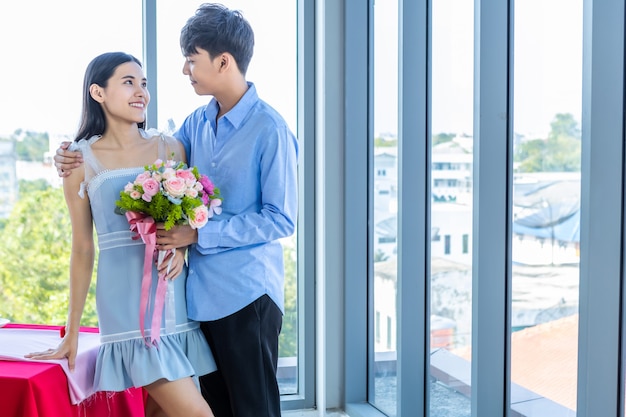 Valentinstag-Konzept, asiatisches junges glückliches süßes Paar, das einen Strauß roter und rosa Rosen nach dem Mittagessen in einem Restauranthintergrund hält, Liebesgeschichtenpaar