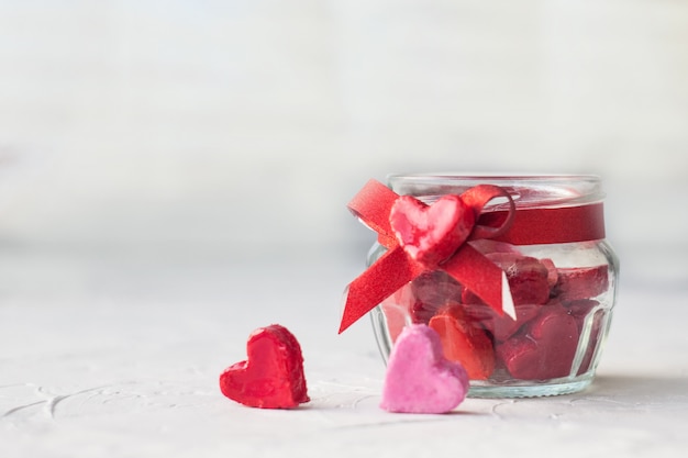 Valentinstag-Konzept. Glas mit kleinen Herzen rot und rosa auf hellem Hintergrund.