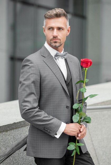 Foto valentinstag konzept grauer smoking mann mit valentinstag rose blume geschenk für valentinstag