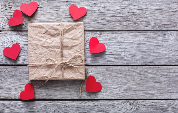 Valentinstag mit handgefertigten Papierherzen und Bastelgeschenkbox auf rustikalem Holz