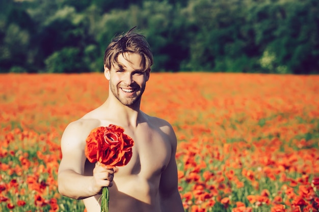 Valentinstag. Nackter Mann mit Blumenstrauß. Muskelkörper im Bereich der roten Mohnblume, Sommer, Drogen- und Liebesvergiftung, Opium.