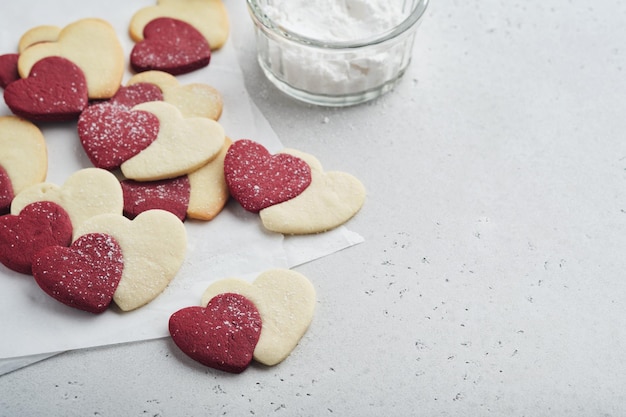 Valentinstag-Plätzchen Shortbread-Kekse in süßen roten Herzen mit Schokoladenglasur auf rosa Platte auf grauem Hintergrund Muttertag Frauentag Süße Feiertage Backen Valentinstagskarte Ansicht von oben