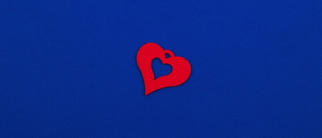 Valentinstag rote Holzherzdekoration hautnah, Urlaub mit Liebe eins, flaches Design, Vorlagenbanner, blauer Hintergrund. Foto in hoher Qualität