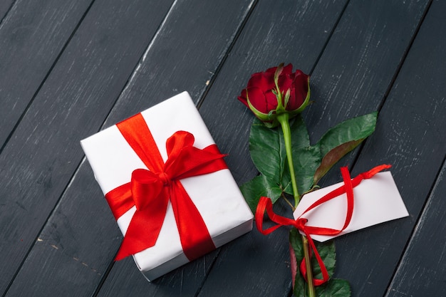 Valentinstag. Rote Rosen und Geschenkbox auf Holztisch