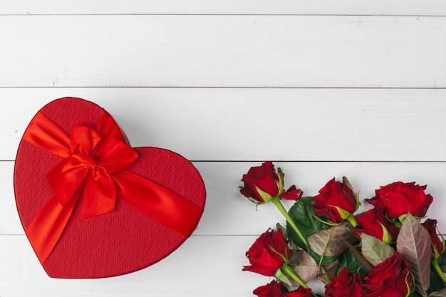 Valentinstag. Rote Rosen und Geschenkbox auf Holztisch