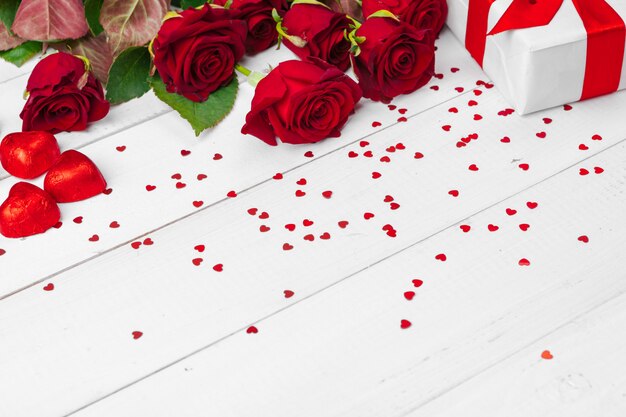 Valentinstag. Rote Rosen und Geschenkbox auf Holztisch