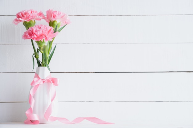 Valentinstag und Liebeskonzept. Rosa Gartennelke im Vase auf hölzernem Hintergrund.