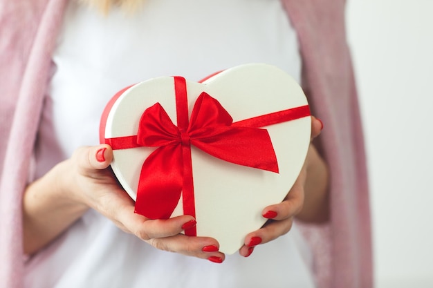 Valentinstag, Urlaub und Geschenkkonzept. Schließen Sie herauf Hände der Frau halten Geschenkbox rotes Herz für Valentines Day.Delivery vorhanden. Überraschung