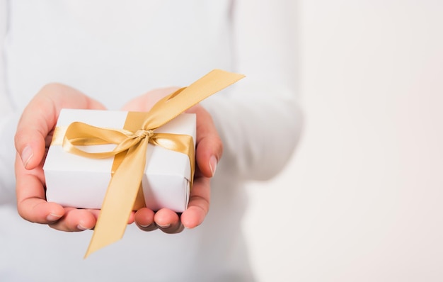 Valentinstag Weibliche Schönheitshände, die kleine Geschenkverpackungsbox präsentieren, verpacktes Papier mit Band