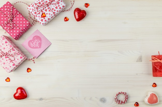 Valentinstag Zusammensetzung mit Geschenkboxen, verschiedenen Herzen und Kerze auf einem hellen hölzernen Hintergrund.