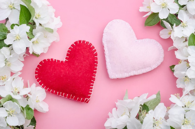 Valentinstag, zwei Herzen auf einem rosa Hintergrund mit Apfelblumen