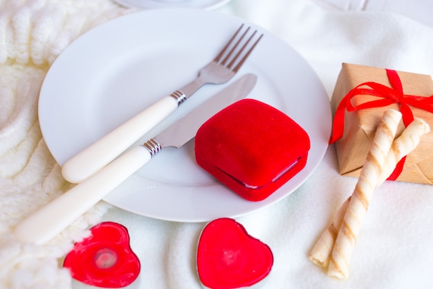 Valentinstaggedeck mit rotem samtringkasten, kerzen und tafelsilber