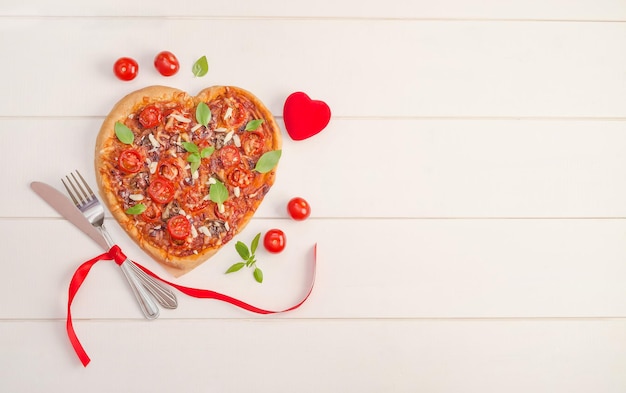 Valentinstaghintergrund mit Pizzaherzen auf weißem hölzernem Hintergrund mit Kopienraum.