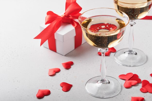 Valentinstaghintergrund mit Sektgläsern und Geschenkbox mit rotem Band. 8. März, Valentinstag, Geburtstag der Mutter der Frauen. Flache Lage, Draufsicht, Kopierbereich.