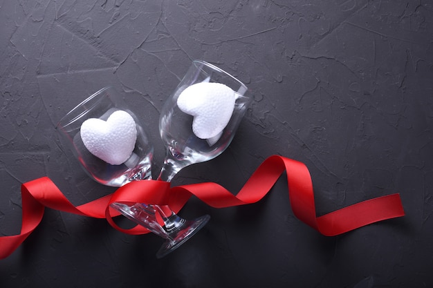 Valentinstaghintergrundgrußkarten-Liebessymbole, rote Dekoration mit Gläsern auf Steinhintergrund. Draufsicht mit Kopienraum und -text Flache Lage