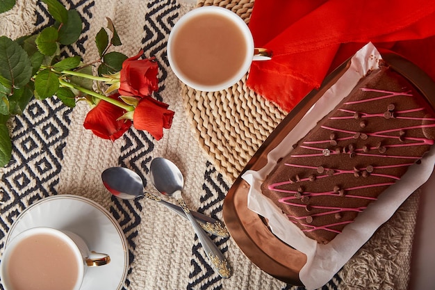 Valentinstagsfeiertagsfrühstück mit Schokoladenkuchenkaffeetassen und roter Rosenästhetik