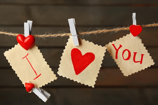 Valentinstagskarte mit Herzen und Worten der Liebe auf Holzhintergrund