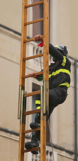 Foto un valiente bombero sobre una escalera de madera durante un ejercicio de extinción de incendios