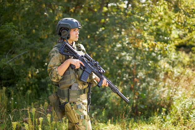 Valiente mujer caucásica se dedica a la caza arma o rifle, vistiendo traje militar