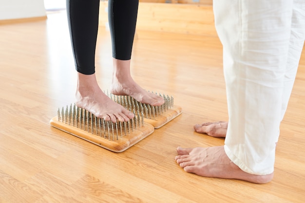 Valiente mujer de pie sobre la cama de uñas en la práctica de yoga