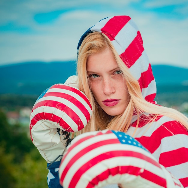 Valiente niña adulta patriota estadounidense en un 4 de julio. La boxeadora de Close Up se está preparando para atacar, vistiendo un traje rojo, blanco y azul, celebrando el Día de la Independencia de los Estados Unidos de América.