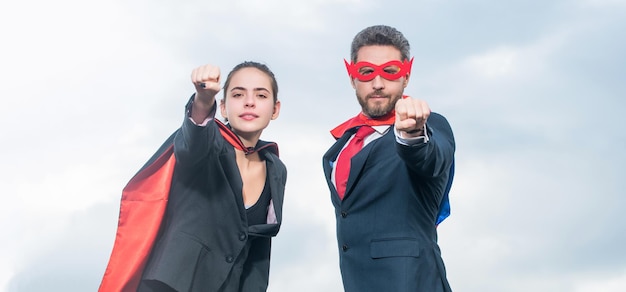 Valiente pareja de negocios en traje de superhéroe sobre fondo de cielo