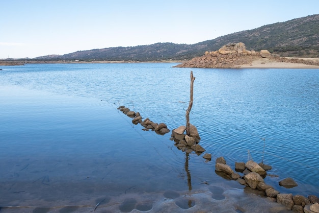 Una valla de alambre de púas sumergida y desgastada entra en el agua de un lago