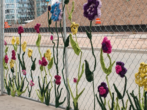 Valla de construcción cubierta con criaturas de jardín de ganchillo como insectos y flores por la Ladies Fancywork Society. Sitio de construcción de Union Station en Denver, Colorado.