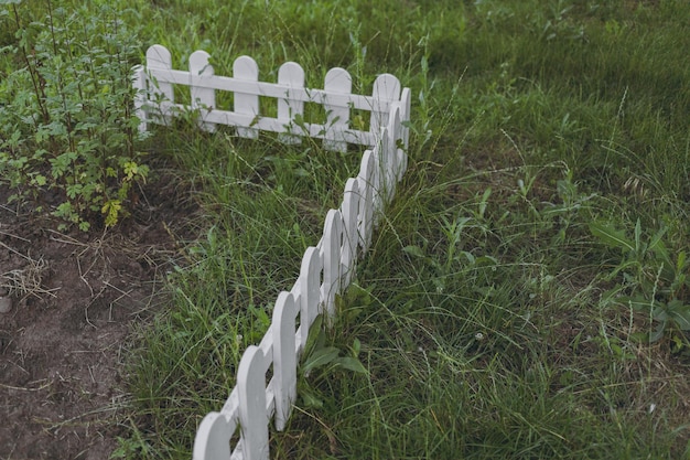 Valla de madera blanca para encerrar macizos de flores.