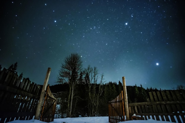 Valla de madera en las montañas con cielo estrellado arriba