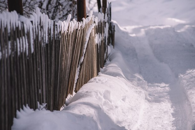 Valla de madera vieja en la nevada y soleada mañana