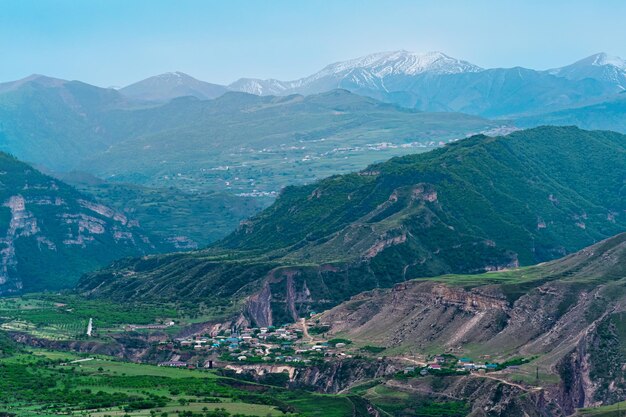 Valle alpino brumoso con asentamientos y campos entre picos de montaña