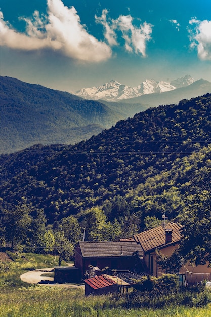 Valle italiano con una pequeña casa y los Alpes en el horizonte