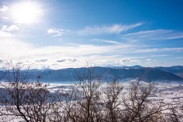 Valle del paisaje invernal y colinas cubiertas de nieve en un día soleado