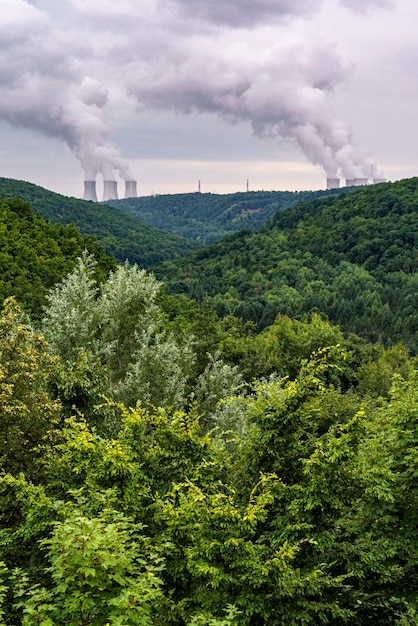 Valle verde y en el horizonte son las torres de enfriamiento de una planta de energía nuclear Dukovany