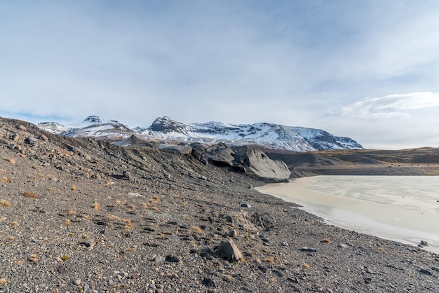 Valles de las montañas lago congelado y pradera cerca del glaciar en Islandia