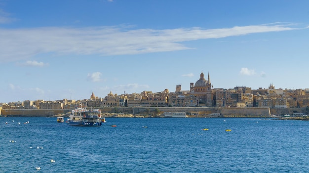 Valletta, Malta - 27 de noviembre de 2017 Horizonte matutino de La Valeta con la Basílica de Nuestra Señora del Monte Carmelo, mar Mediterráneo con ferry y barco antiguo visto desde Sliema, Malta.