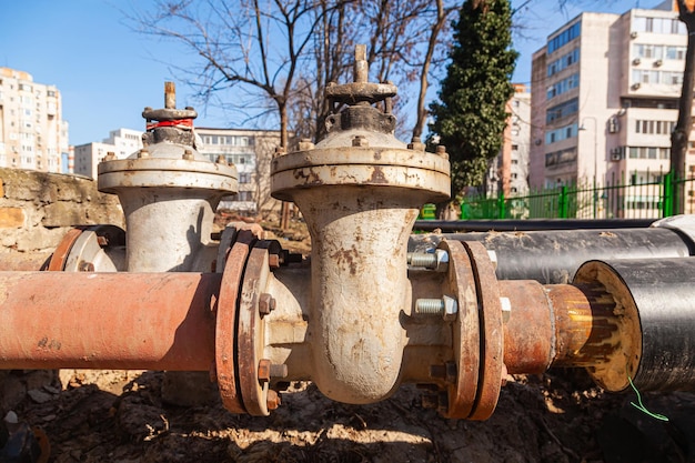 Válvulas de gaveta nas juntas dos tubos de aquecimento isolados com materiais isolantes perto da área residencial