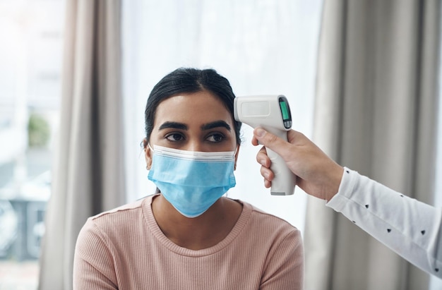 Vamos a comprobar si tiene fiebre Toma de un médico irreconocible que usa un termómetro para tomar la temperatura de un paciente en un consultorio