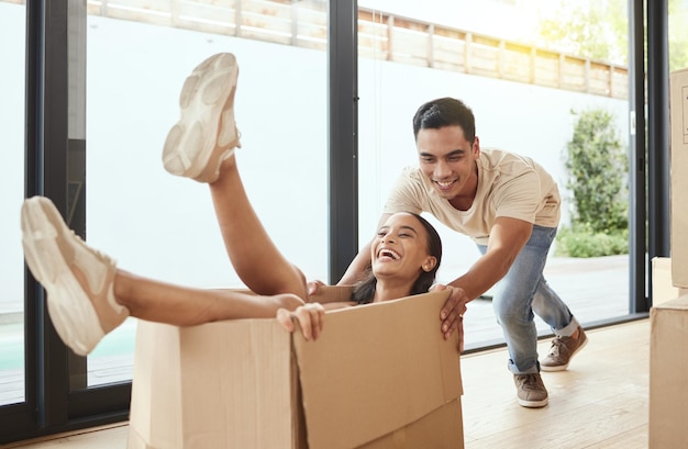 Vamos nos divertir muito aqui Foto de um jovem casal brincando em sua nova casa