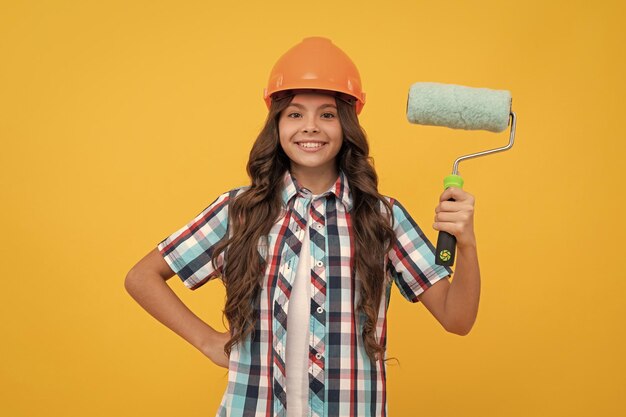 Vamos a trabajar niña adolescente feliz sostenga niño rodillo de pintura en cepillo de rodillo de casco para la decoración