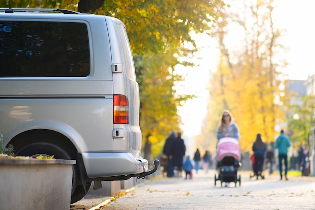 Van parkte an einem hellen Herbsttag auf einer Straßenseite der Stadt mit unscharfen Menschen, die auf der Fußgängerzone spazieren.