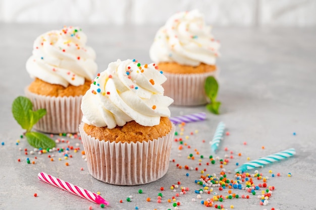 Vanille Cupcakes mit Frischkäse und Kandiszucker auf grauem Hintergrund Dessert zum Geburtstag