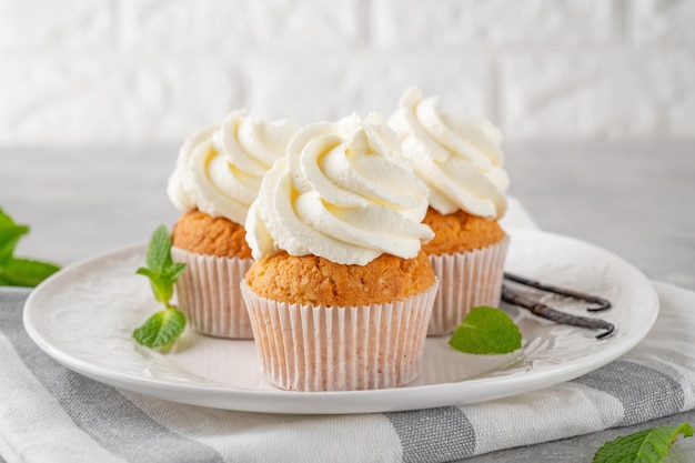 Vanille Cupcakes mit Frischkäse und Kandiszucker auf grauem Hintergrund Dessert zum Geburtstag