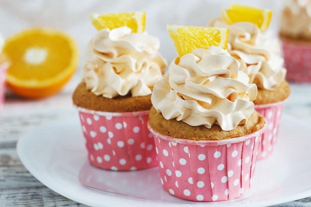 Vanillekleine kuchen mit einer Kappe der Creme auf weißem hölzernem tablein