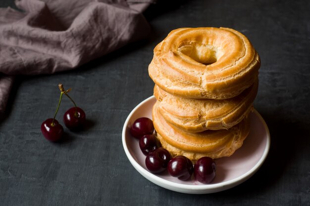 Vanillepuddingkuchen schellt mit Kirsche auf einer Platte auf Dunkelheit