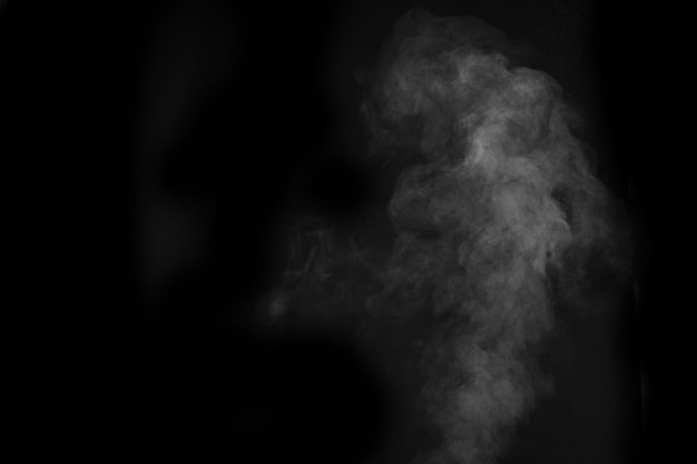 Vapor blanco rociado de vapor del saturador de aire. Fragmentos de humo sobre un fondo negro. Fondo abstracto, elemento de diseño, para superposición de imágenes