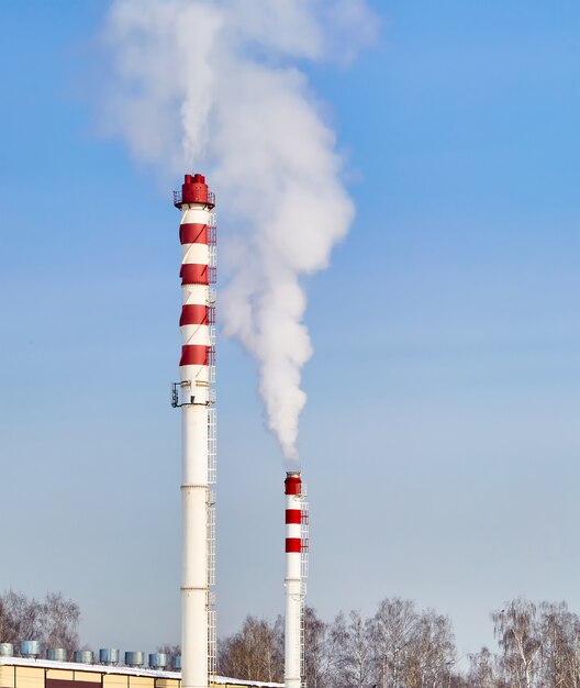 Vapor de canos para aquecer um edifício contra um céu azul. paisagem da cidade. foto vertical.